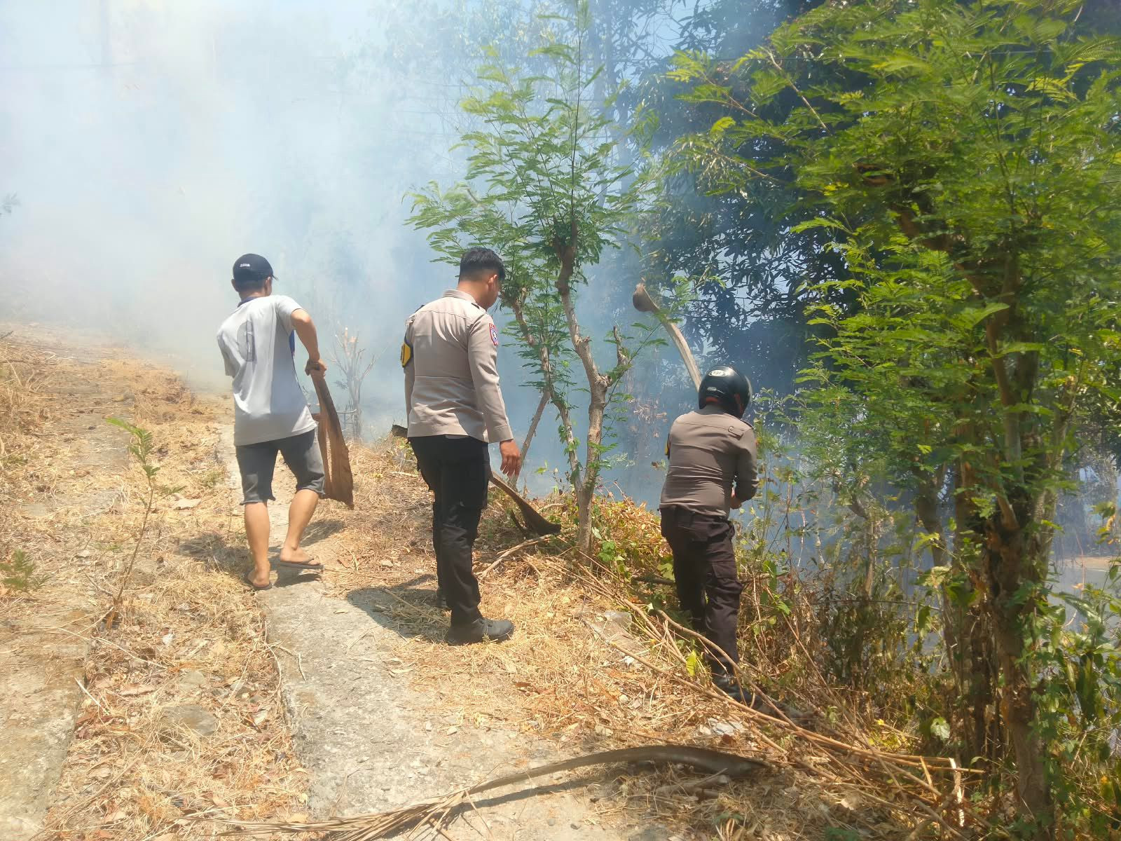Ketgam: Polisi bersama warga berjibaku memafamkan api yang membakar lahan kosong di Pamboang. (Dik. Kamil)